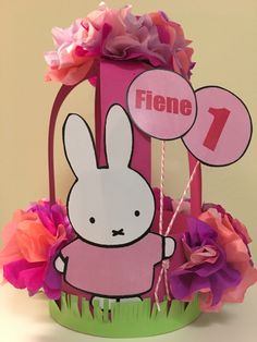 a paper basket filled with flowers and a bunny on it's side, next to a sign that says fiene