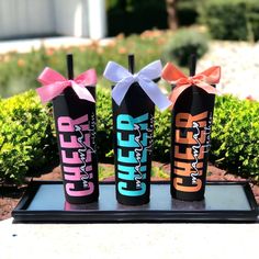 three different flavored drink cans with bows on them sitting in front of some bushes