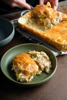 a person is cutting into a casserole on a plate