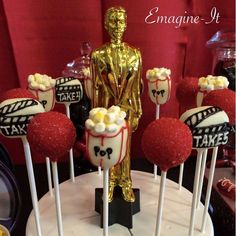 some cake pops are sitting on top of a table with an oscar statue in the background