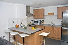 a modern kitchen with stainless steel appliances and wooden cabinets, along with white tile flooring