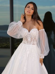 a woman in a wedding dress posing for the camera with her hand on her hip