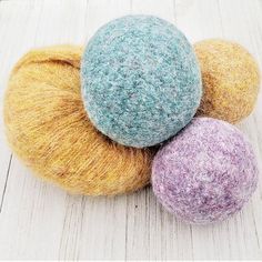 three balls of yarn sitting on top of each other in different colors and sizes,