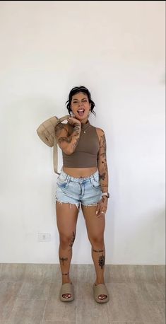 a woman with tattoos standing in front of a white wall