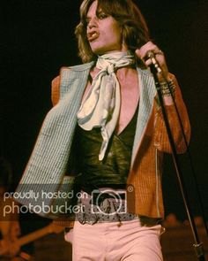 an image of a man that is on stage with a microphone and wearing pink pants