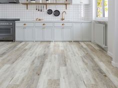 a kitchen with white cabinets and wood flooring on the walls is pictured in this image