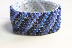 This layered bracelet was made by embellishing a netted base of Japanese seed beads with a mix of blue Swarovski crystals, glass pearls, and fire polished beads.   It's 7 1/4 inches long and 1 1/8 inch wide and closes with a silver toned magnetic slide clasp. Thanks so much for looking!! Blue Beaded Bracelets With Spacer Beads For Party, Handmade Blue Crystal Beaded Bracelets, Blue Beaded Crystal Bangle Bracelet, Elegant Blue Beaded Crystal Bracelet, Blue Crystal Beaded Bracelets With Faceted Beads, Blue Crystal Bracelet With Round Beads, Blue Beaded Crystal Bracelet For Jewelry Making, Blue Beaded Crystal Bracelet With Round Beads, Blue Crystal Beaded Bracelets