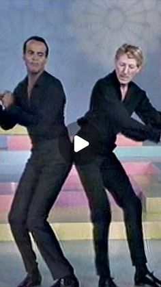 two men in black suits are dancing together