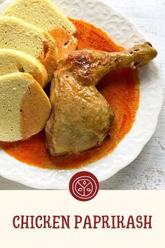 chicken papirash on a white plate with red sauce and bread slices in the middle