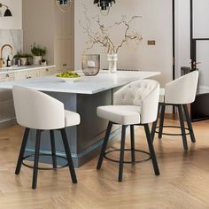 a kitchen with an island and bar stools next to the counter top, in front of a dining room table