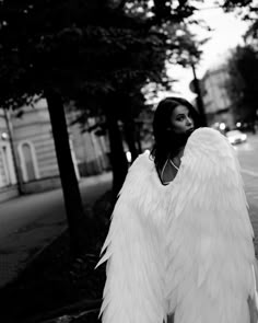 a woman in an angel costume is standing on the sidewalk