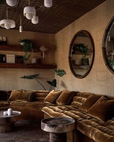 a living room with couches, tables and two mirrors hanging from the ceiling above them