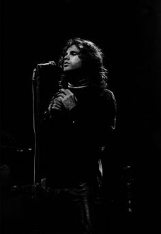 a black and white photo of a person holding a microphone in front of a stage