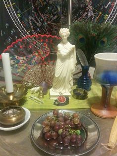 there is a plate with grapes on it and a statue in the background next to candles