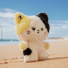 a small stuffed animal sitting on top of a sandy beach