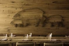 a wooden table topped with glasses next to a drawing of a rhino on the wall