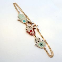 a gold chain bracelet with three charms on it and an evil eye charm hanging from the clasp