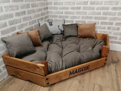 a couch made out of wooden pallets with pillows on it and the word maggie written in black