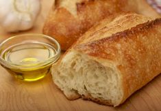 two pieces of bread sitting on top of a cutting board next to a bowl of oil