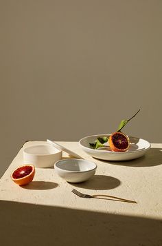 two white bowls filled with fruit on top of a table