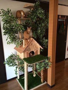 a cat tree house with two cats on top and one in the middle, surrounded by greenery