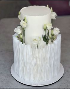 a three tiered white cake with flowers on top