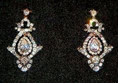 two pairs of diamond earrings sitting on top of a black surface