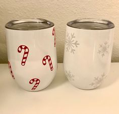 two white cups decorated with candy canes and snowflakes