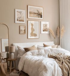 a bed with white linens and pillows in a neutral colored bedroom, surrounded by pictures on the wall