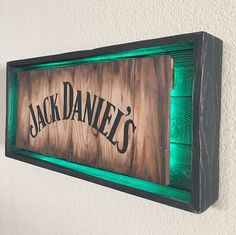 a wooden sign with the word jack daniels painted on it's side and green light underneath