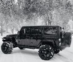 a black jeep driving down a snow covered road