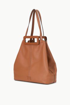 The Grande Tote Bag is a soft, unlined tote with top handles and longer over-the-shoulder straps for versatility. It includes an interior closure on the gussets to bring in the sides of the bag to create a different shape and a removable zip pouch.