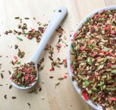 a bowl filled with colorful sprinkles next to a spoon on top of a wooden table