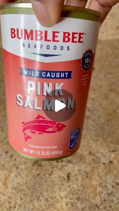 someone holding up a can of pink salmon