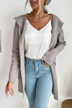 a woman with blonde hair wearing jeans and a white top is standing in front of a wall