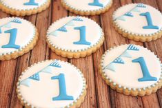 decorated cookies with blue and white frosting are arranged on a wooden surface, including one number