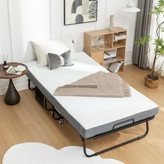 a bed sitting on top of a wooden floor next to a white chair and table