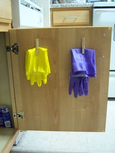 two oven mitts hanging on a wooden cabinet