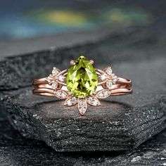 a ring with a green stone surrounded by white diamonds on top of a black rock