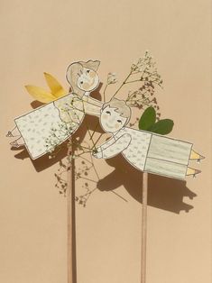 three wooden sticks with paper cut out of them on top of each other and flowers in the middle