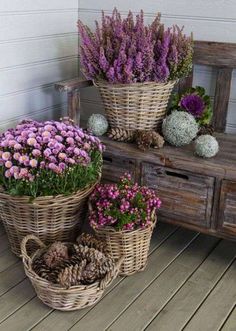 three baskets filled with flowers sitting on top of a wooden floor next to a bench