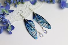 A must have for all fairies! A truly beautiful pair of ocean blue transparent fairy wing earrings, adorned with shimmering gems and Swarovski droplet crystals. The wings are available in two sizes - please choose your desired option. The earrings photographed are 5cm. The hooks are nickel and lead free! If you're looking for neutral coloured wings which match every outfit, this is the ideal pair for you! This delicate array of fairy wings is really rather lovely. It is perfect for all fairy lovers - whether to be worn as part of a costume, or simply as jewellery to wear everyday. I love wearing mine - I receive so many lovely comments, and I get to feel like a fairy all day! They are super light weight, and flexible to touch - and far more durable than their glassy appearance would suggest Blue Fairy Jewelry For Party, Blue Fairy-style Jewelry For Party, Fairy Wing Earrings, Fairycore Fairy, Earrings Butterfly, Fairy Gifts, Ear Candy, Fairy Wings, Wing Earrings