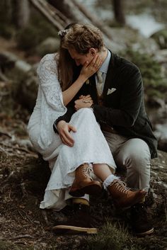 a man and woman sitting next to each other in the woods