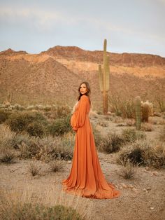 a woman in an orange dress standing in the desert