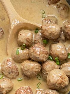 meatballs and gravy in a pot with a wooden spoon