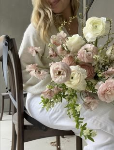 a woman sitting on a chair holding a bouquet of flowers