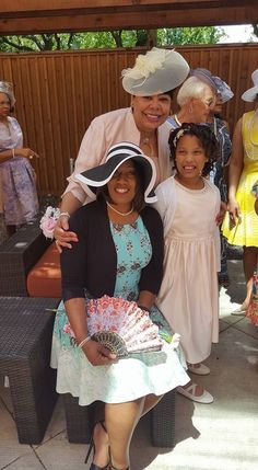 a woman and two children are posing for a photo with some ladies in dresses and hats