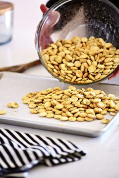 a person pouring peanuts into a pan on top of a counter