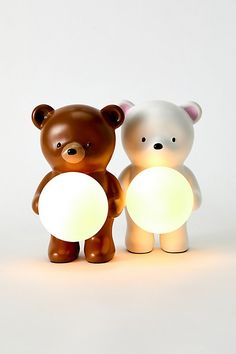 two brown and white teddy bears are next to each other, one is holding a light