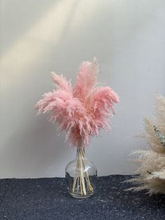 a vase filled with pink feathers on top of a table